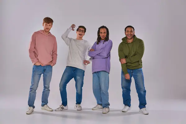 Quatre jeunes hommes multiculturels en tenue décontractée debout et riant à la caméra, diversité culturelle — Photo de stock