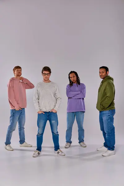 Four young friends in casual trendy outfits standing looking at camera on grey backdrop, diversity — Stock Photo