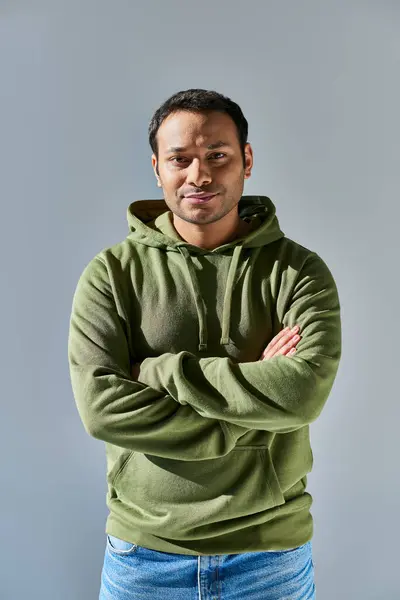 Young indian man in khaki hoodie smiling with his hands crossed on chest on yellow background — Stock Photo