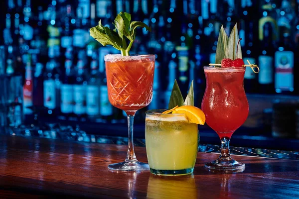Glasses of three different refreshing cocktails with decorations on bar counter, concept — Stock Photo