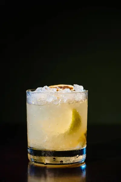 Tropical exotic caipirinha with ice and lemon garnishing on black background, concept — Stock Photo