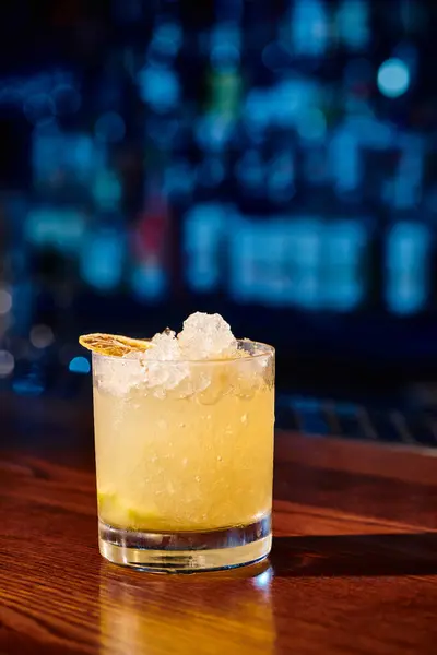 Glass of icy refreshing caipirinha with lemon garnishing with bar on backdrop, concept — Stock Photo