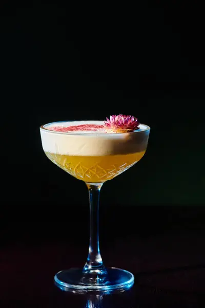 Delicious frothy daiquiri with pink fresh flower on foam on black backdrop, concept — Stock Photo