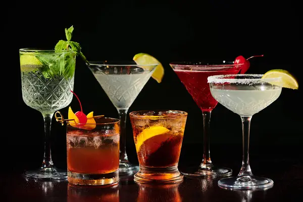Fünf durstlöschende pikante Cocktails mit frischen Garnierungen auf schwarzem Hintergrund, Konzept — Stockfoto