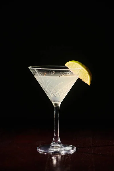 Sofisticado martini delicioso con rodaja de lima fresca sobre fondo negro, concepto - foto de stock