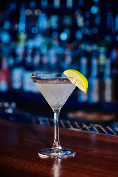 Sed de enfriamiento vaso de cóctel de martini con rodaja de lima fresca en el mostrador del bar, concepto - foto de stock
