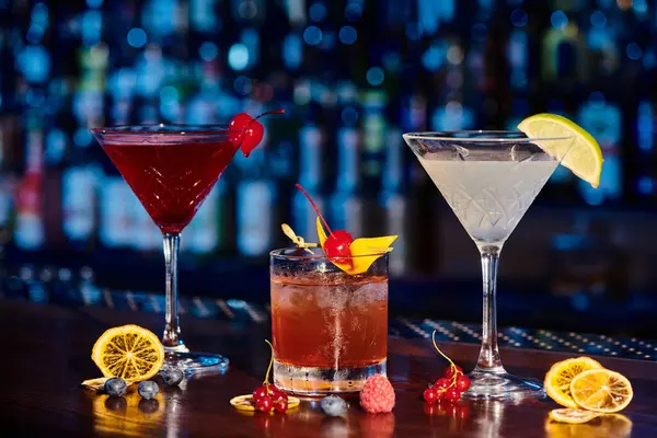 Освежающий мартини, негрони и космополит на барной стойке со свежими ягодами, концепция — стоковое фото