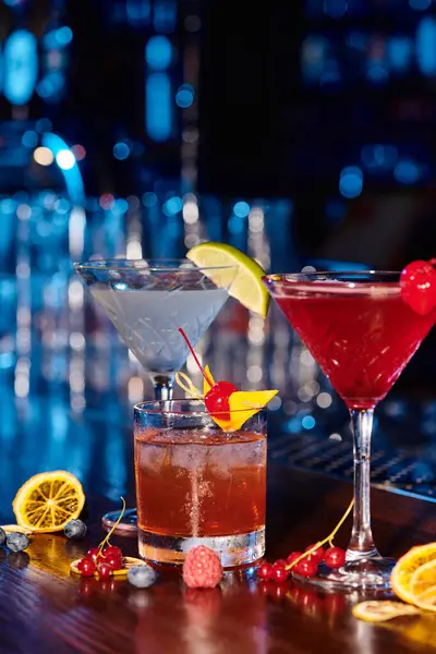 Drei elegante leckere Cocktails auf Theke mit Beeren vor Barkulisse, Konzept — Stockfoto