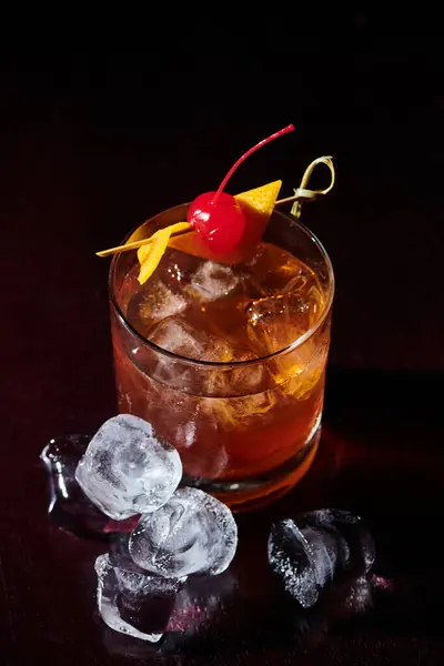 Durstlöschende Negroni mit Cocktailkirsche und Eiswürfeln auf schwarzem Hintergrund, Konzept — Stockfoto