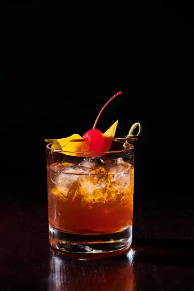 Eiskalte intensive negroni garniert mit cocktail kirsche auf schwarzem hintergrund, konzept — Stockfoto
