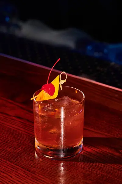 Glace verre sophistiqué froid de negroni décoré avec cerise sur comptoir bar, concept — Photo de stock