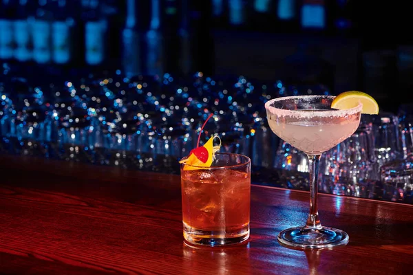 Bebidas alcohólicas sofisticadas adornadas con cal y cereza con el telón de fondo del bar, concepto - foto de stock