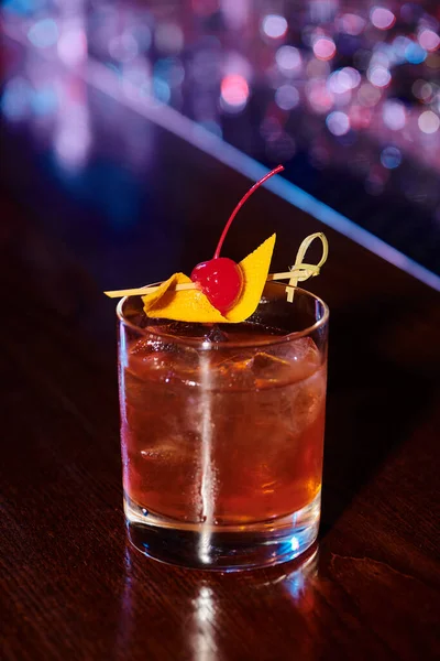 Эстетический элегантный коктейль негрони, украшенный вишней с баром на заднем плане, концепция — стоковое фото