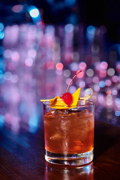 Sophisticated ice cold glass of negroni garnished with cherry with bar backdrop, concept — Stock Photo