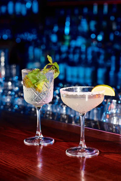 Elegante Gläser leckerer Cocktails mit Dekoration und Bar im Hintergrund, Konzept — Stockfoto