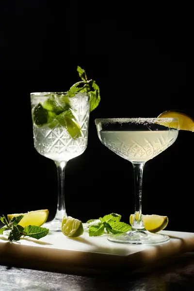Zwei ästhetische Cocktails mit Minz- und Limettenscheiben auf schwarzem Hintergrund, Konzept — Stockfoto