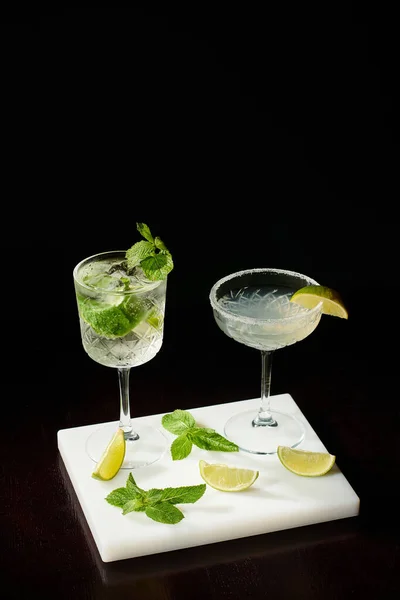 Ästhetische Durstlöscher-Cocktails in eiskalten Gläsern auf schwarzem Hintergrund, Konzept — Stockfoto