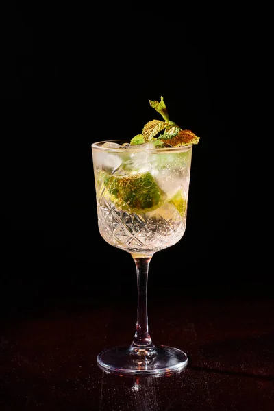 Ice cold glass of bohemian rhapsody decorated with lime and mint on black backdrop, concept — Stock Photo