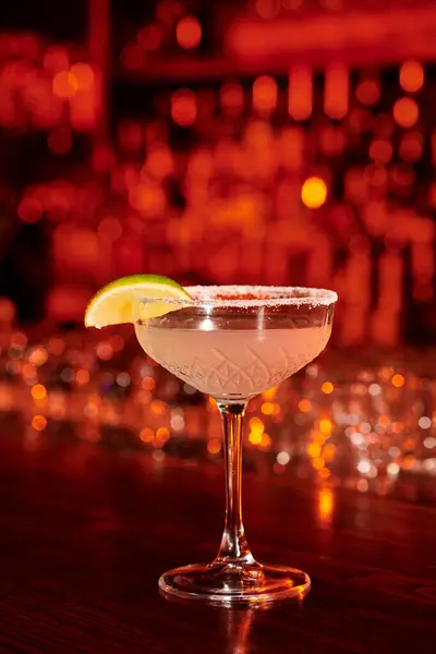 Изысканный коктейль Маргарита украшенный ломтиком лайма и льдом на барной стойке, концепция — стоковое фото