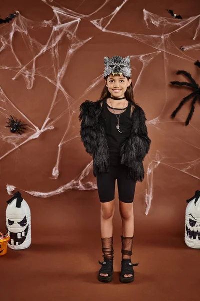 Sorrindo bonito preteen menina em máscara de lobo no fundo marrom com aranhas e web, Halloween — Fotografia de Stock