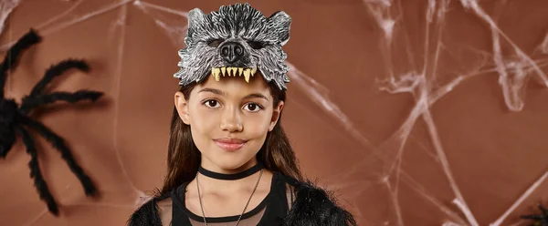 Lächelndes Mädchen auf braunem Hintergrund mit schwarzer Spinne an Halloween, Nahaufnahme, Banner — Stockfoto