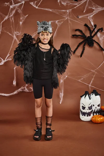 Menina bonito em traje preto e máscara assustadora entre aranhas, lanternas e teias de aranha, conceito de Halloween — Fotografia de Stock
