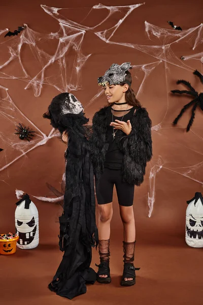 Niña preadolescente sosteniendo juguete de Halloween sobre fondo marrón con arañas, web y linternas, Halloween - foto de stock