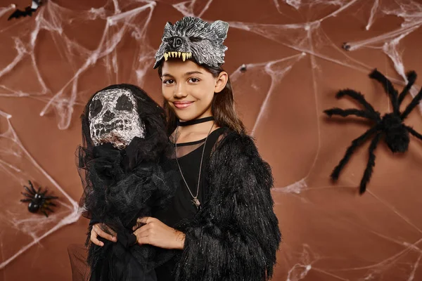 Nahaufnahme lächelndes preteen girl hält gruseliges Spielzeug auf braunem Hintergrund, Halloween-Konzept — Stockfoto