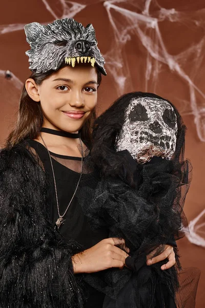 Portrait of smiling preteen girl holding scary Halloween toy on brown backdrop, Halloween, close up — Stock Photo