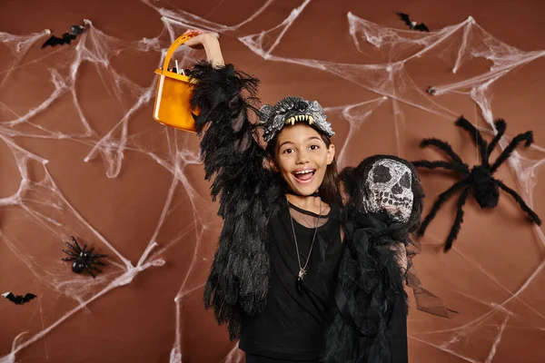 Menina pré-adolescente alegre gritando e segurando brinquedo assustador e balde de doces, conceito de Halloween — Fotografia de Stock