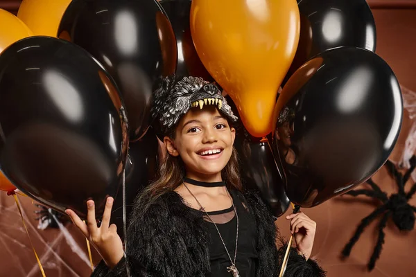 Retrato de linda niña preadolescente rodeada de globos negros y naranjas, concepto de Halloween - foto de stock