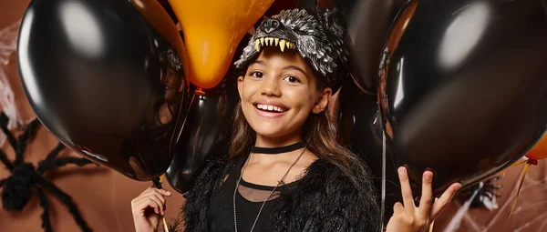 Закрыть счастливую дочку в окружении черных и оранжевых воздушных шаров, концепция Хэллоуина, баннер — стоковое фото