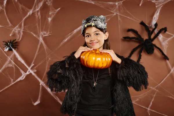 Muito preteen menina segurando abóbora sob seu queixo no fundo marrom, conceito de Halloween — Fotografia de Stock