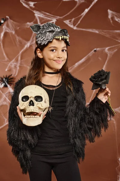 Close up sorrindo menina pré-adolescente segura rosa preta e crânio em suas mãos usando máscara de lobo, Halloween — Fotografia de Stock