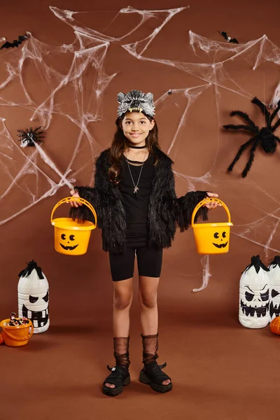 Happy girl with two pumpkin buckets with lanterns, cobweb and spiders, Halloween concept — Stock Photo