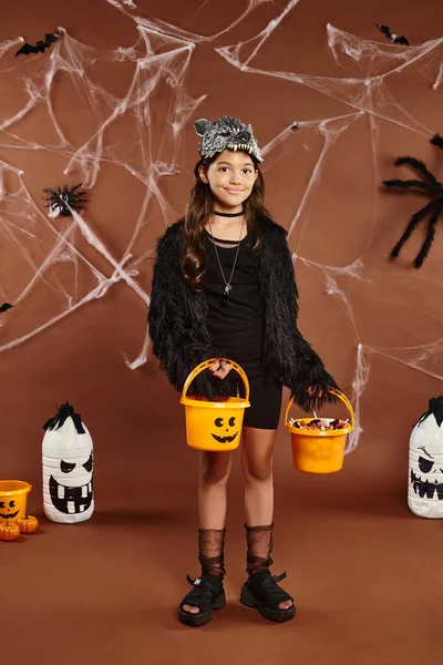 Criança alegre na máscara de lobo mantém dois baldes de doces com morcegos e aranhas no pano de fundo, Halloween — Fotografia de Stock