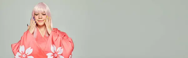 Mulher cosplay satisfeito com peruca loira e manicure colorido posando em quimono rosa no cinza, banner — Fotografia de Stock