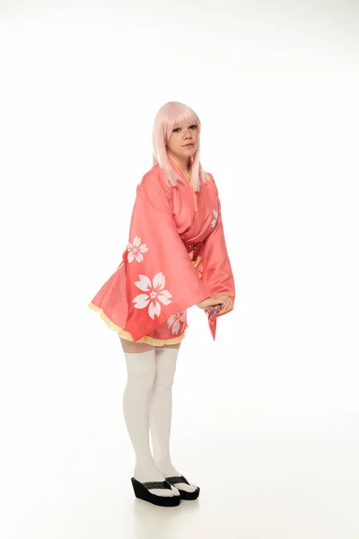 Comprimento total de jovem modelo com cabelo loiro posando em quimono rosa e meias de joelho branco no branco — Fotografia de Stock