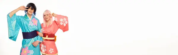 Alegre estilo anime pareja en brillantes kimonos mostrando signo de victoria en blanco, bandera horizontal - foto de stock