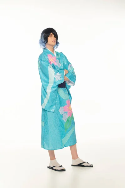 Полная длина молодого человека в красочном кимоно и парике, позируя со скрещенными руками на белом, косплеере — стоковое фото