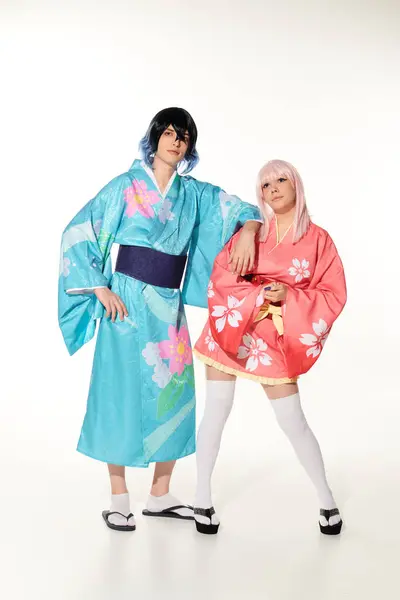 Полная длина молодой и яркой пары в кимоно и париках на белой, азиатской субкультуре косплея — стоковое фото