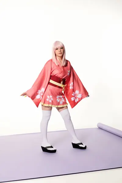 Japanese cosplay subculture, blonde woman in kimono and wig on purple carper and white backdrop — Stock Photo