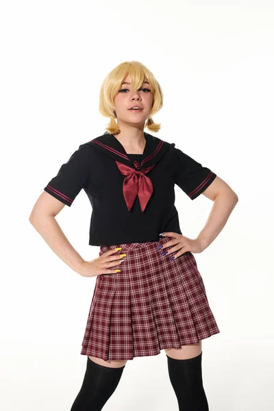 Confident woman in yellow blonde wig and school uniform with hands on hips on white, cosplay concept — Stock Photo