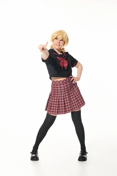 Yellow blonde woman in school uniform standing with hand on hip and pointing at camera on white — Stock Photo