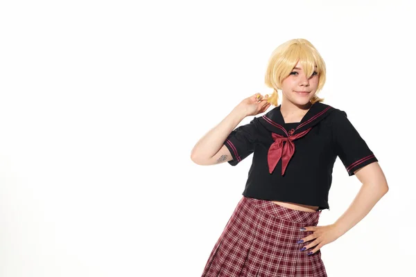 Sorrindo anime estilo mulher na escola uniforme segurando a mão no quadril e olhando para a câmera no branco — Fotografia de Stock