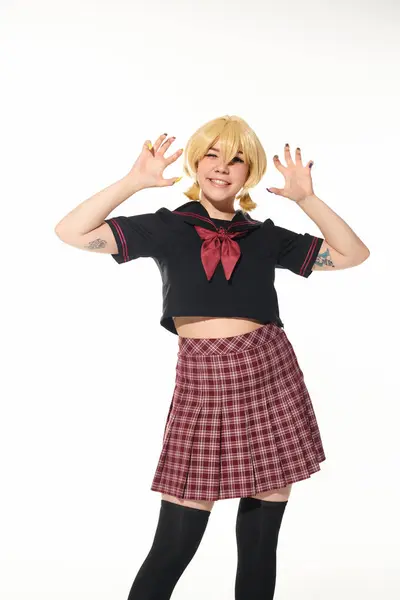 Funny cosplay woman in yellow blonde wig and school uniform showing scaring gesture on white — Stock Photo
