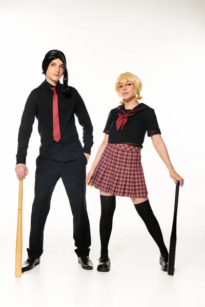 Couple of cosplayers in school uniform and wigs with baseball bats on white, full length — Stock Photo