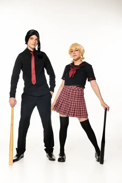 Coppia di cosplayers in uniforme scolastica e parrucche con mazze da baseball su bianco, lunghezza intera — Foto stock