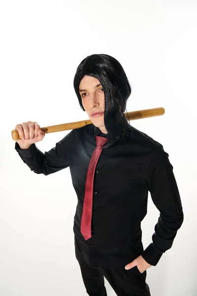 Уверенный в себе человек в черном парике и красном галстуке держа бейсбольную биту и глядя на белый, стиль аниме — стоковое фото