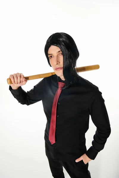Confident man in black wig and red tie holding baseball bat and looking away on white, anime style — Stock Photo